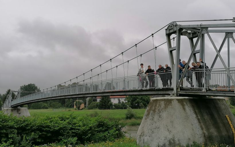 Eine Gruppe winkt bei einem Ausflug von einer Brücke.