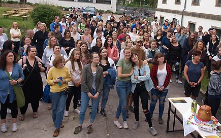 Schülerschaft der DPFA Dresden steht im Hof der Schule und grüßt in die Kamera.