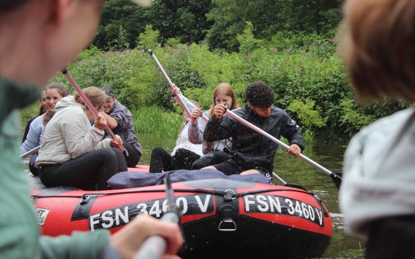 Schülerinnen und Schüler der Erzieherausbildung der DPFA Chemnitz paddeln in einem Schlauchboot.