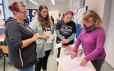 Schüler:innen der Erzieherausbildung der DPFA Dresden schauen sich verschiedene Praxismappen an.