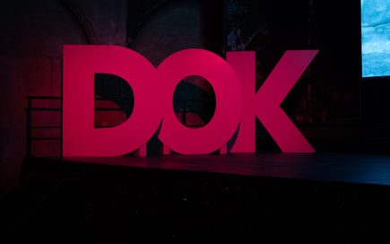 Alles ist schwarz. In leuchtend dunkelroten Lettern ist das Wort eines Filmfestivals geschrieben "DOK".